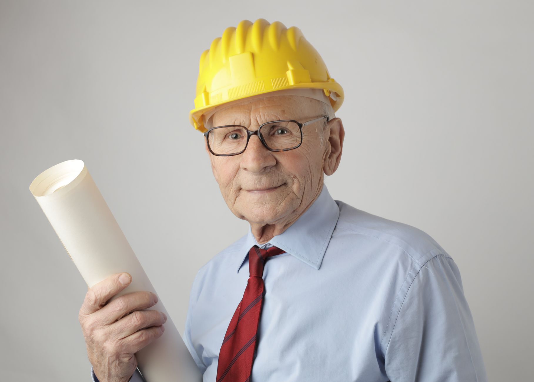 Senior engineer in safety gear holding blueprints, symbolizing experience and dedication in civil engineering.