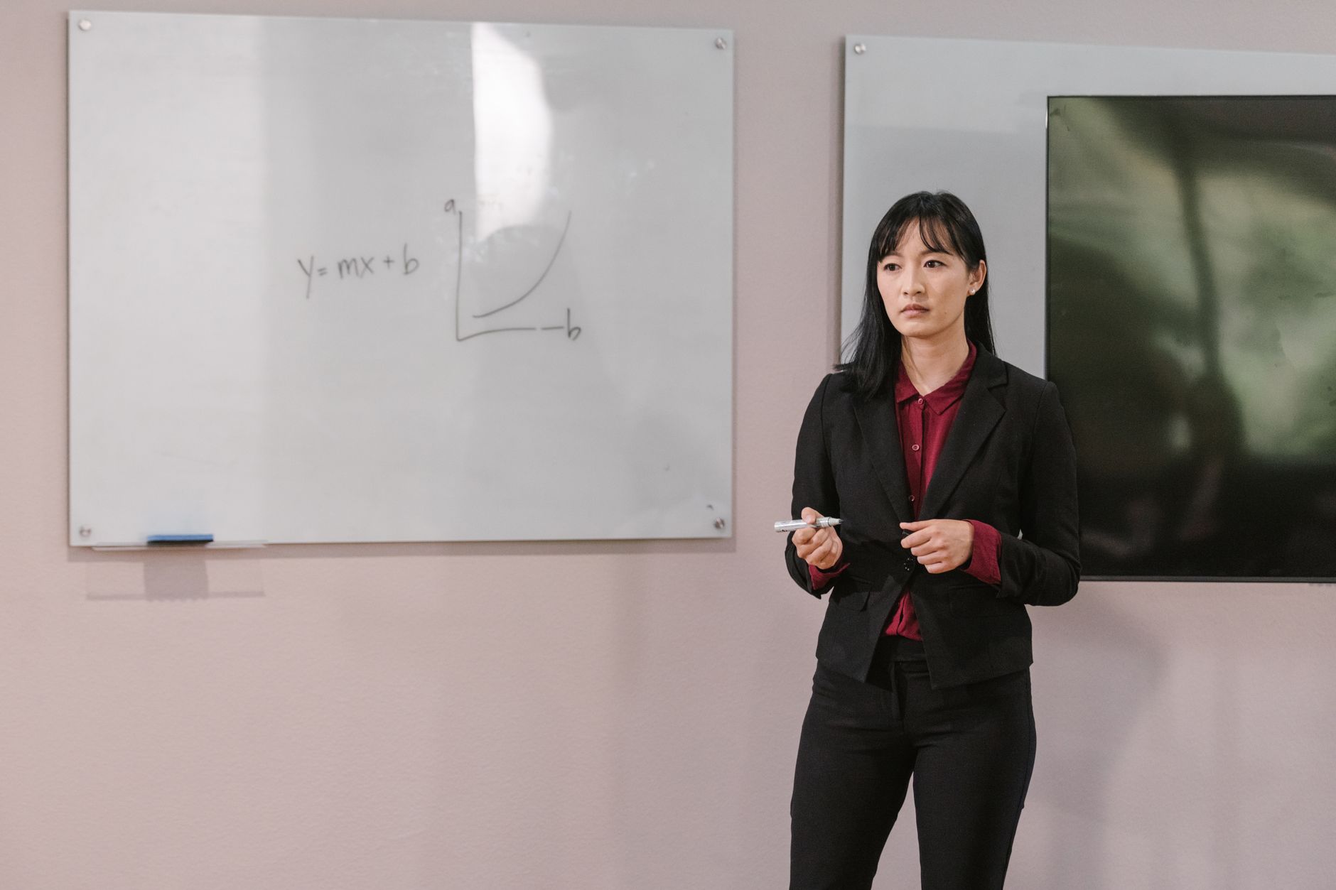 Businesswoman presenting on a whiteboard explaining financial concepts indoors.