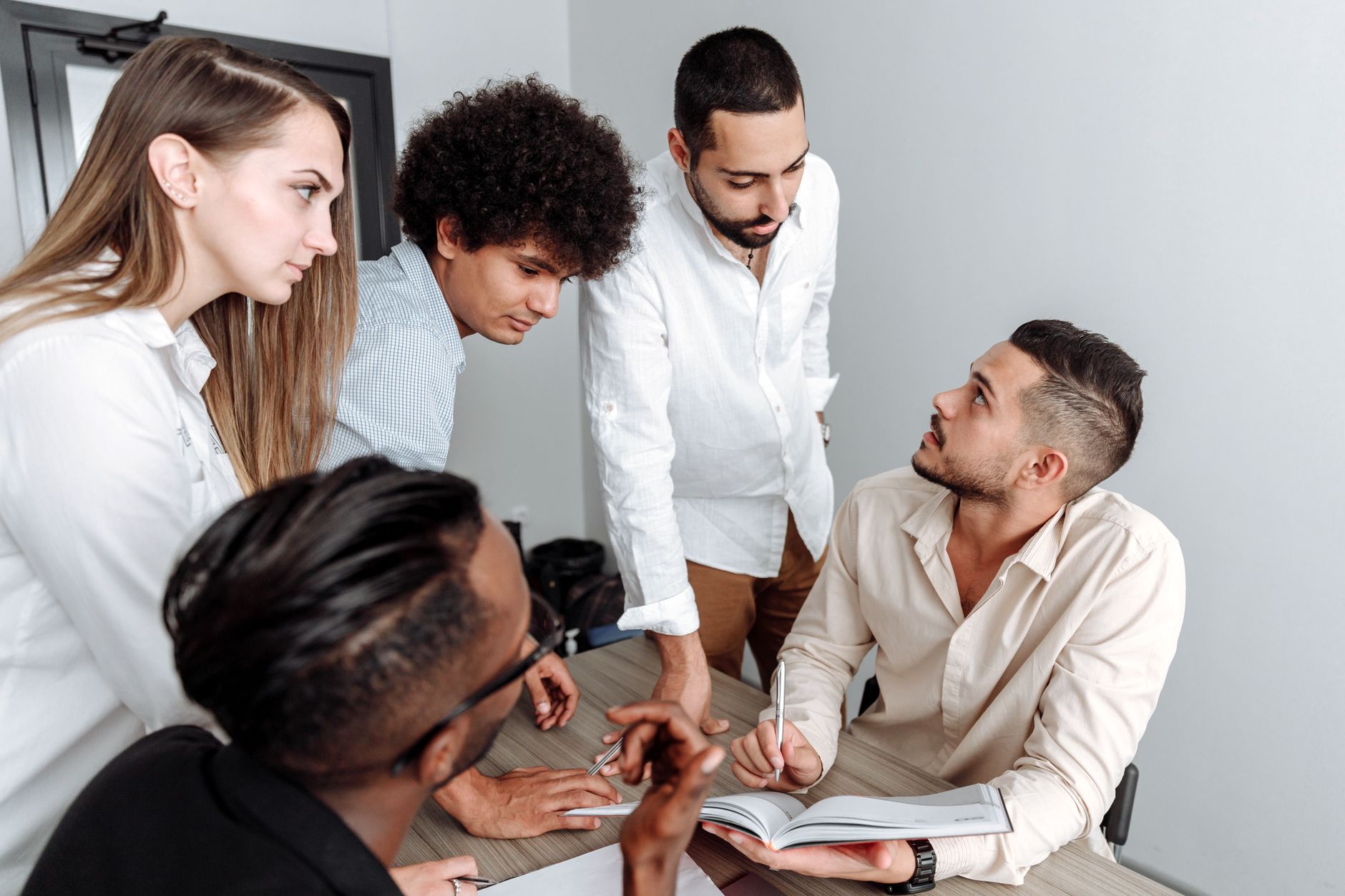 A diverse group of professionals engaged in a team discussion in a modern office setting.