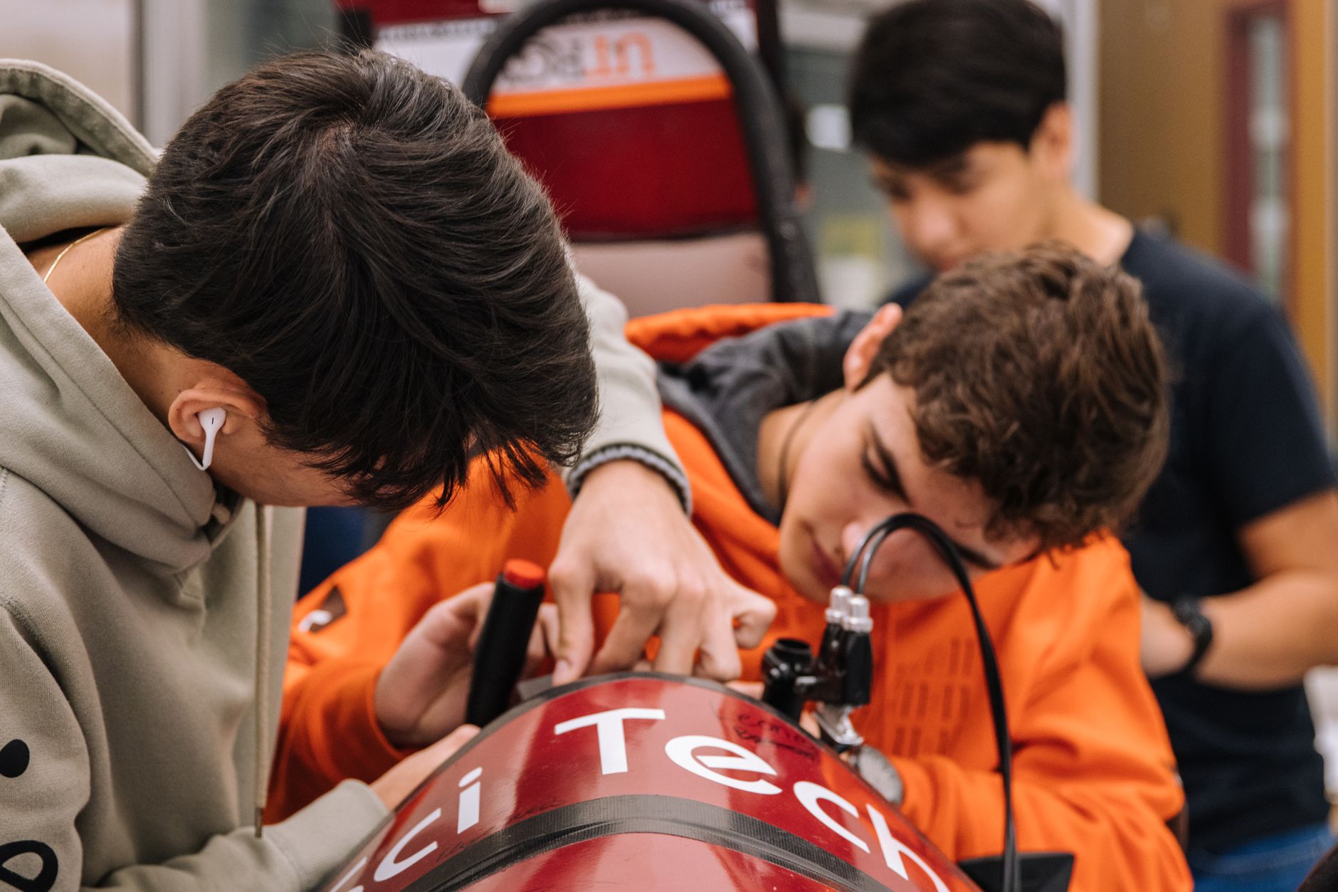 Teenagers engaged in a hands-on engineering project at a workshop, focusing on teamwork and innovation.