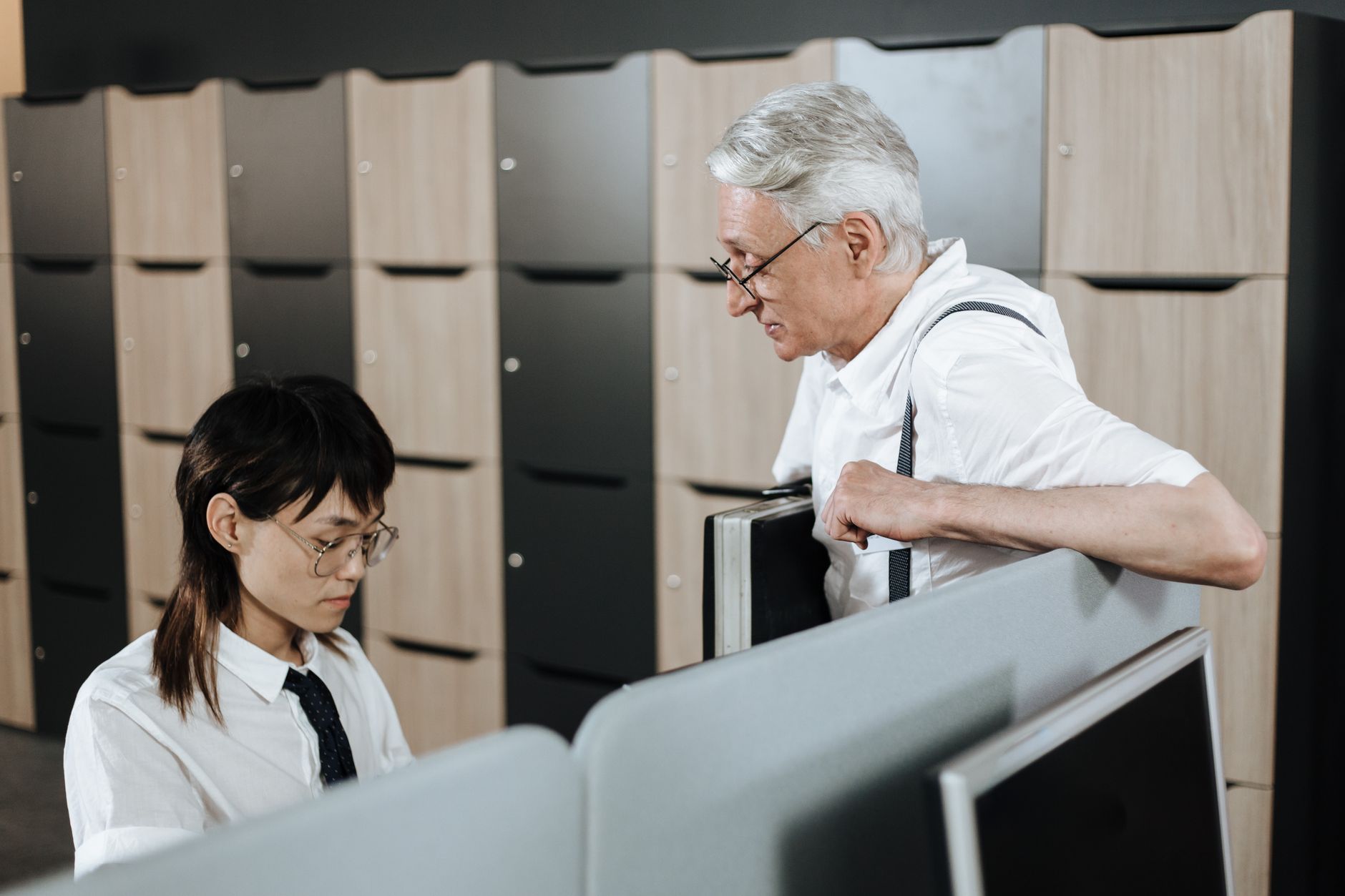 Senior professional engaging with young colleague in an open office setting.