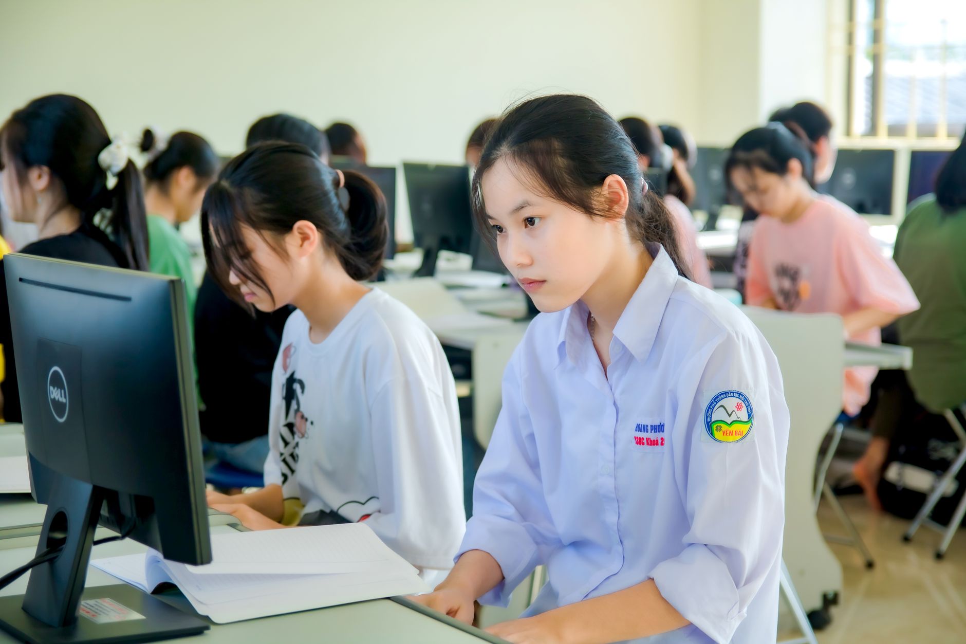 A group of students focused on computer screens in a modern classroom setting.