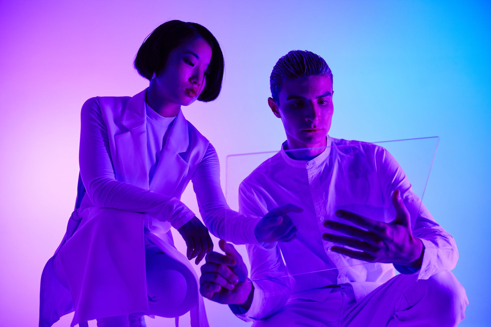 A man and woman engaging with a transparent holographic screen in a modern studio setting.