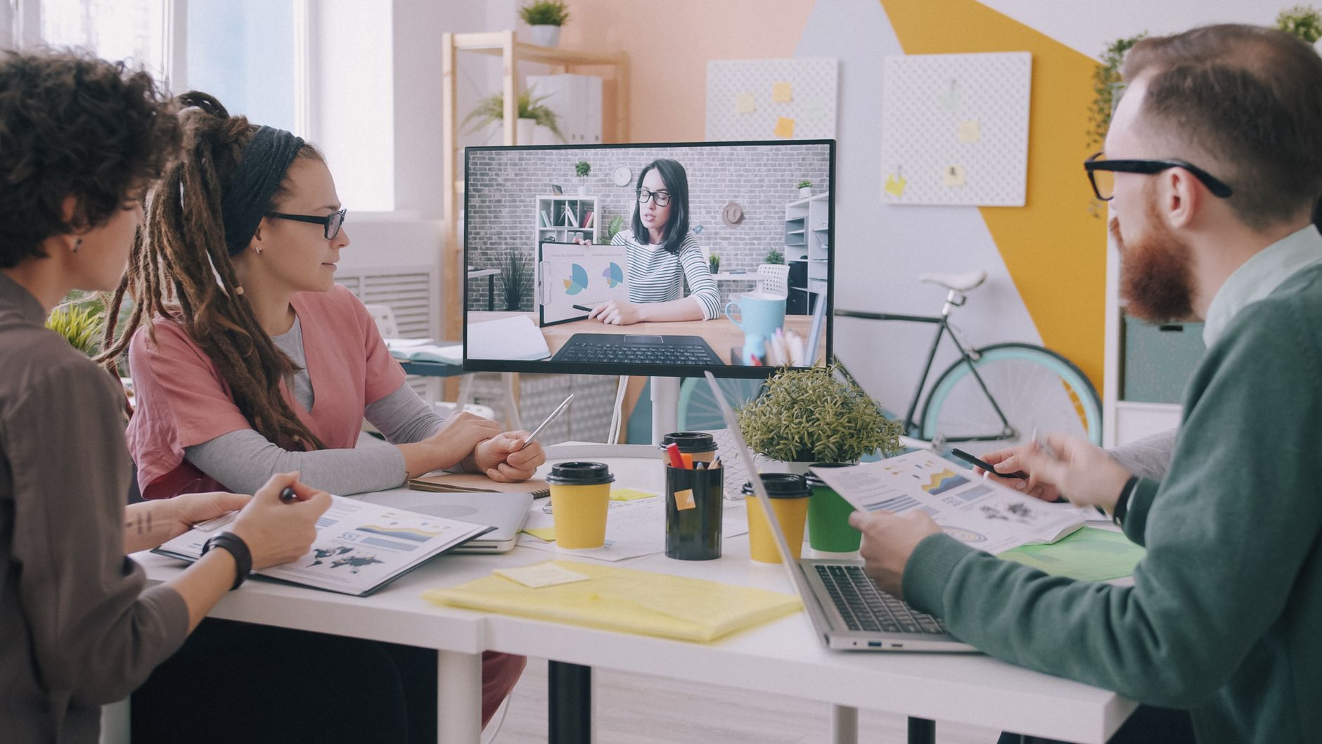 Creative team in a modern office engaged in a video conference meeting, discussing business strategies.