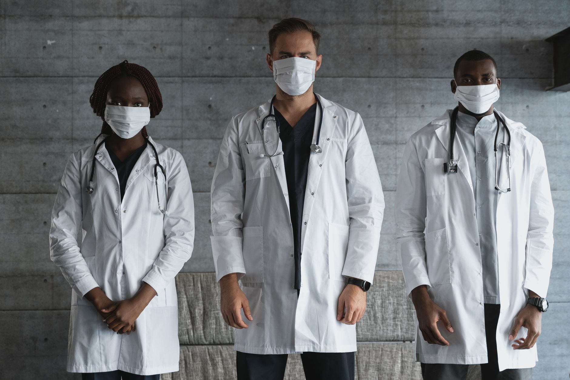 A diverse group of doctors in white coats and masks standing indoors, signifying unity in healthcare.