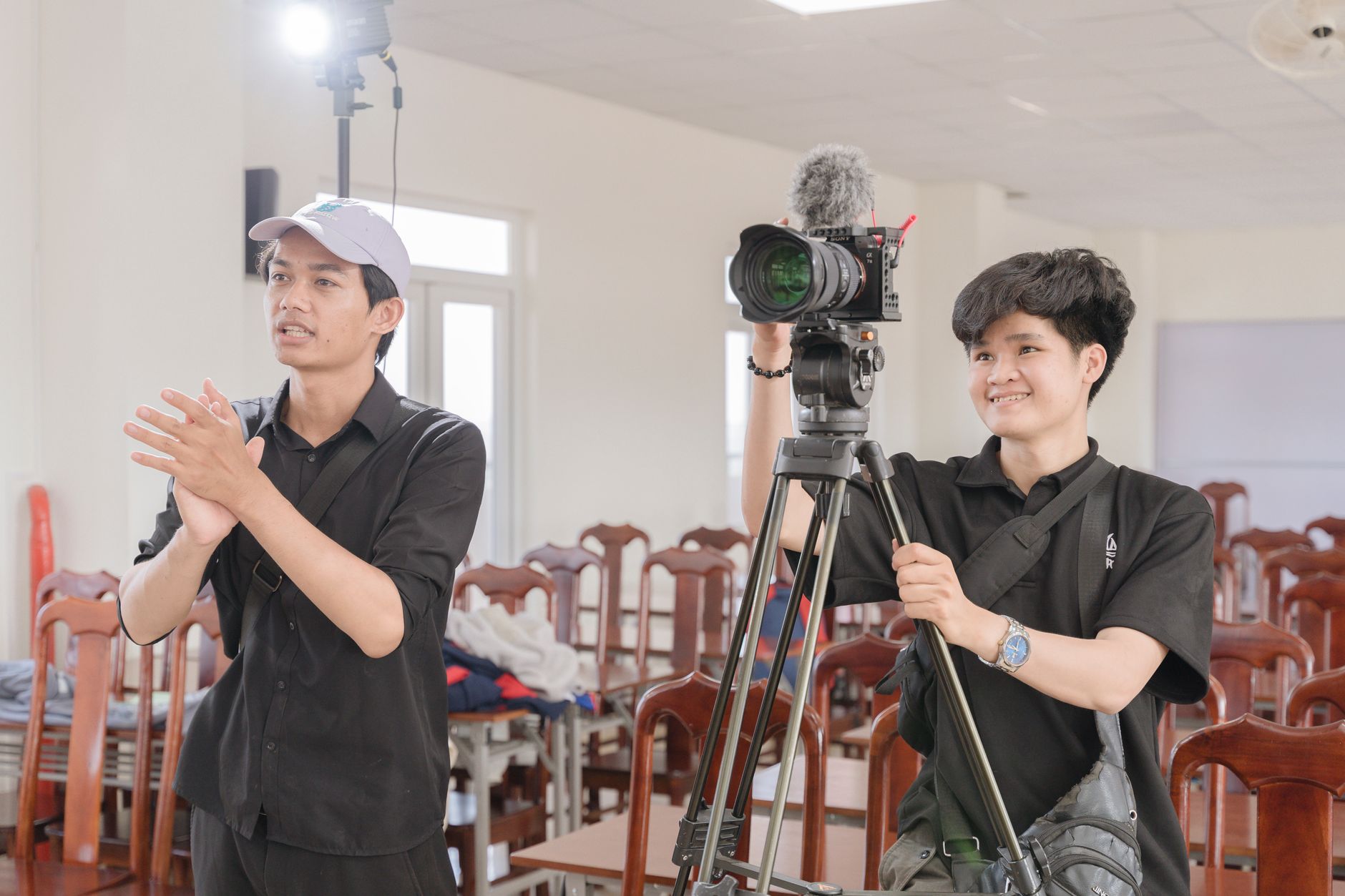 Two young filmmakers working with a camera in a bright studio.