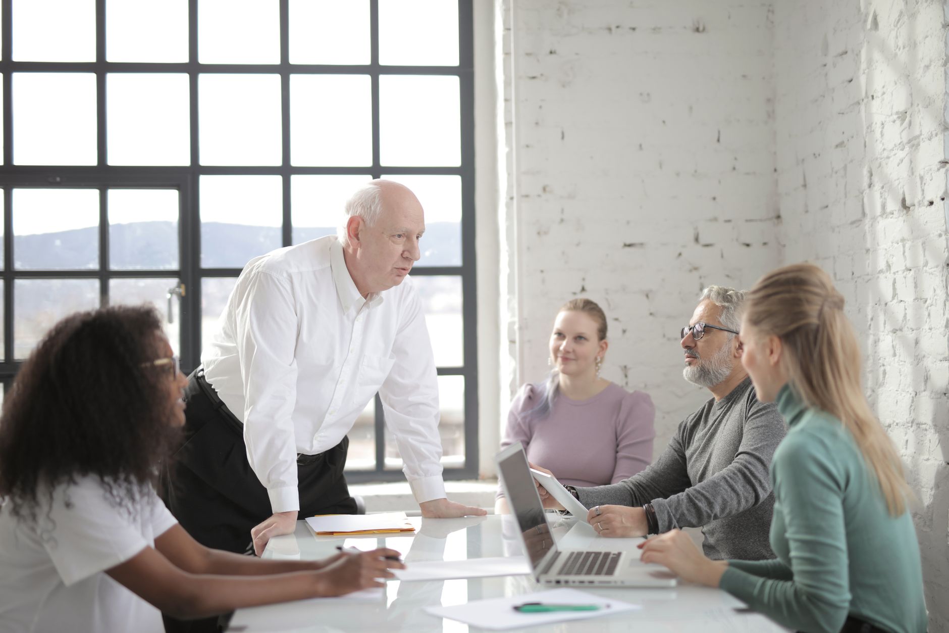 Concentrated team leader standing while explaining business project to colleagues during work in modern workspace in daytime looking at each
