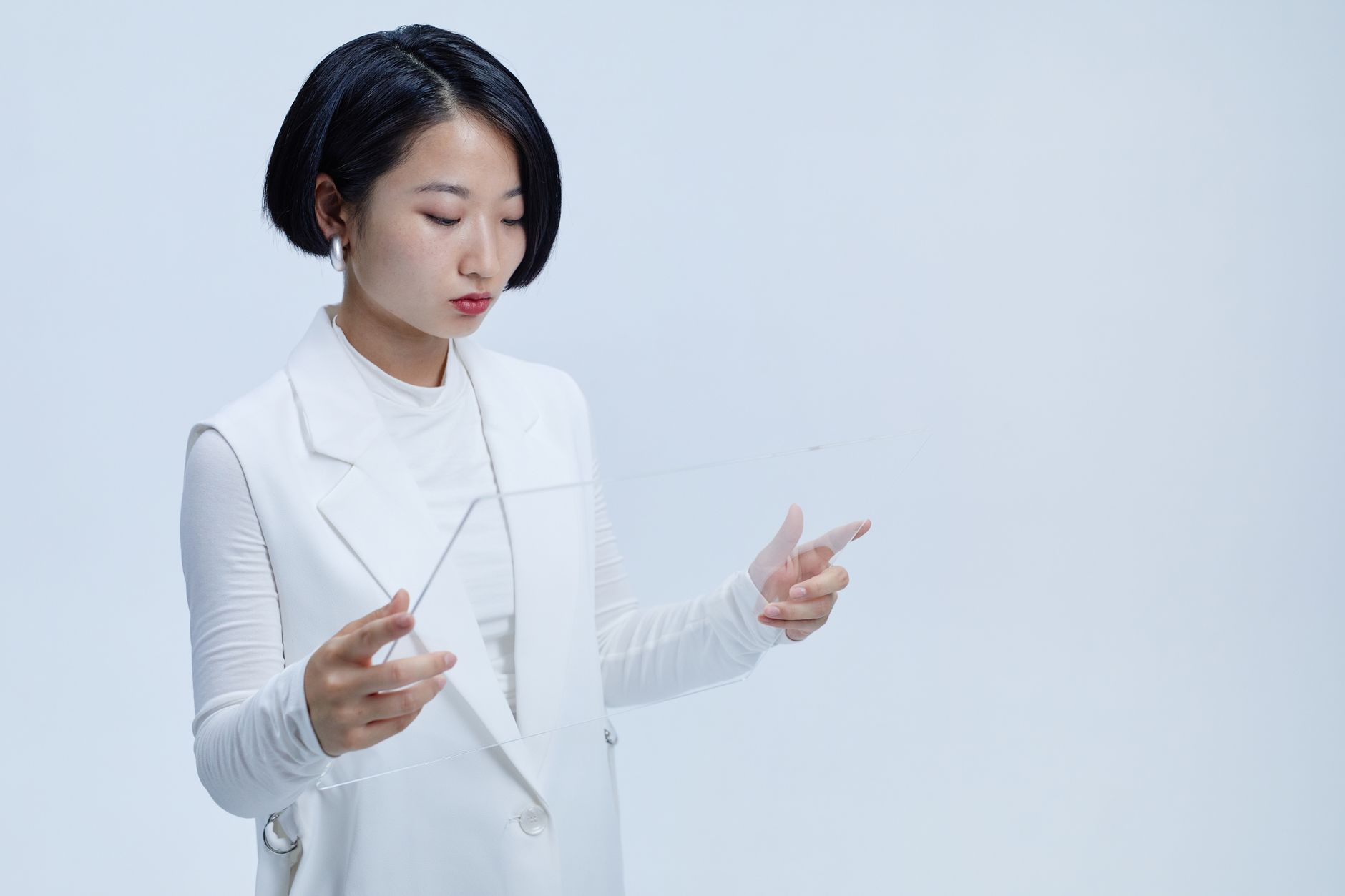 Young woman interacting with a futuristic transparent screen, showcasing modern technology concepts.